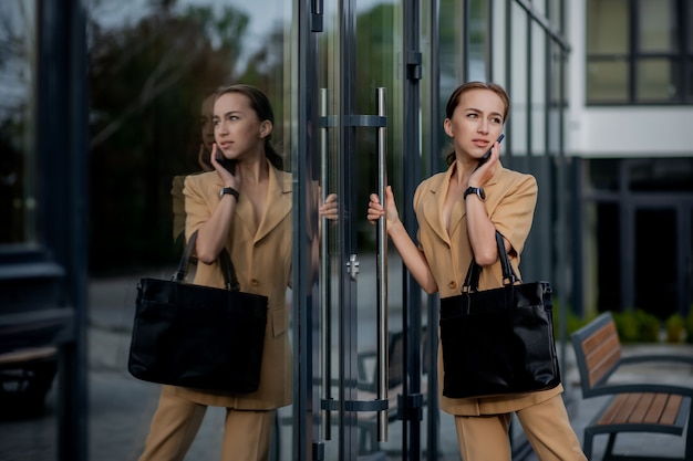 Closeup Portrait of an businesswoman standing outside office building and speaking mobile phone.