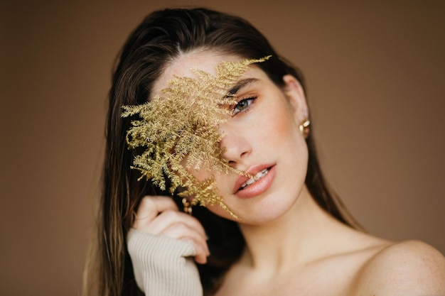 Closeup portrait of cheerful brunette girl with flower Positive european lady with black hair looking to camera