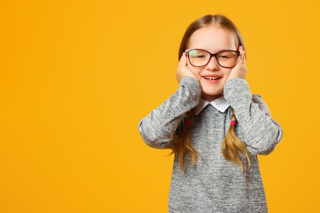 Closeup portrait of a cheerful little girl on yellow background