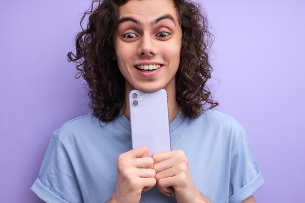 Closeup portrait of cheerful smiling guy taking photo on smartphone holding mobile phone closely to ...