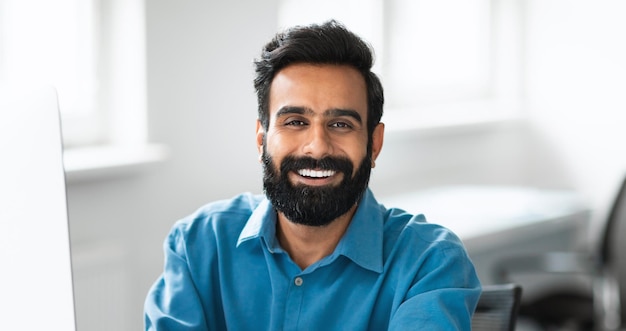 Closeup portrait of confident indian businessman working in office interior looking at camera and