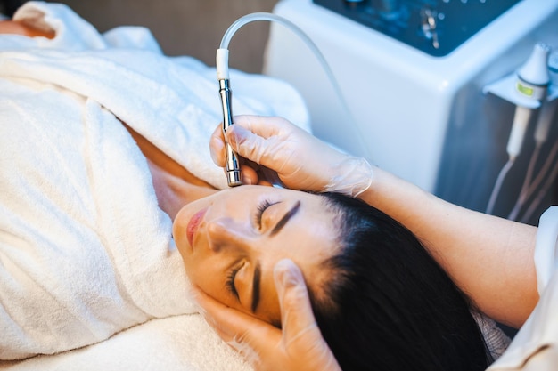 Photo closeup portrait of cosmetologists hands making microdermabrasion procedure on the face of a woman i...