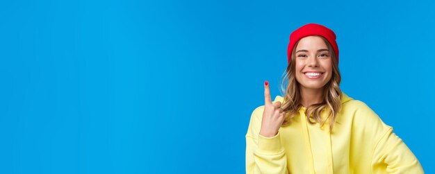 Closeup portrait of cute optimistic european female in red beanie and yellow hoodie showing number o