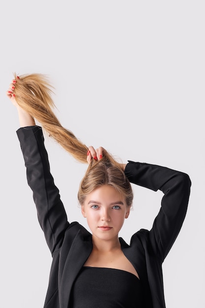 Closeup portrait of cute woman playing with her long straight hair lifting them up