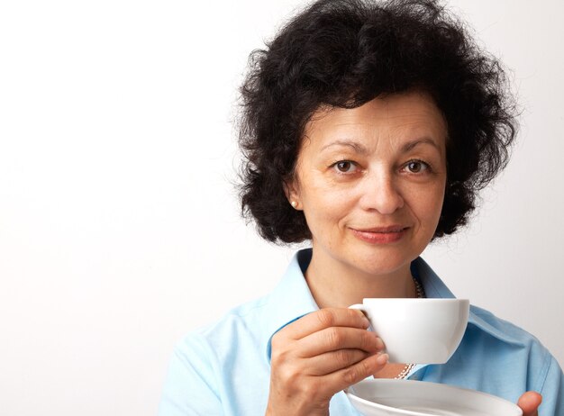 Closeup portrait of an elder smiling woman holding cup and saucer.