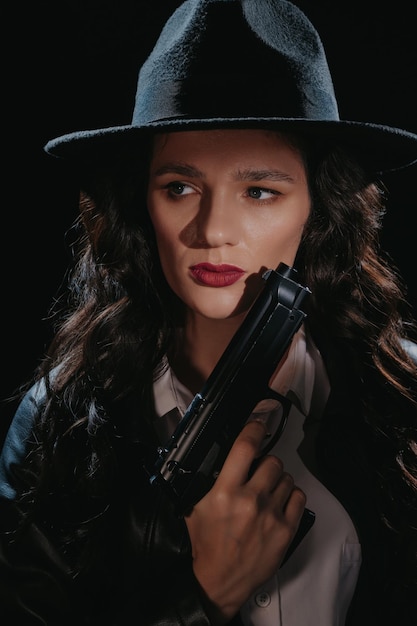 Photo closeup portrait of a female detective in a coat and hat with a gun in her hands