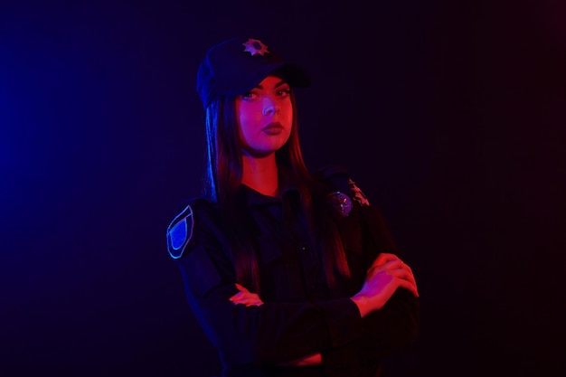 Closeup portrait of a female police officer posing for the camera against a black background with re...