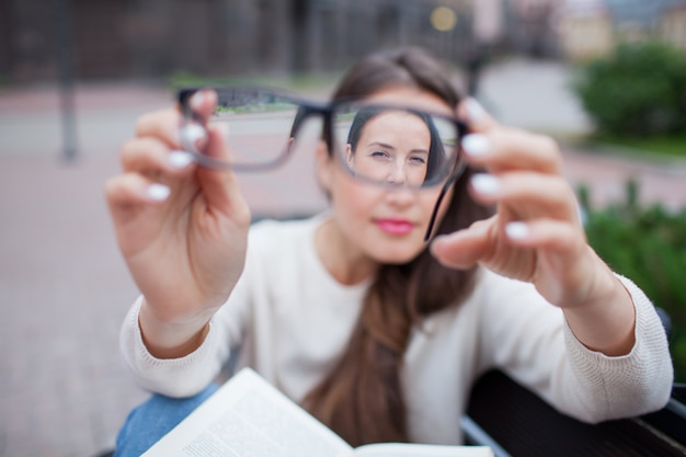 Closeup portrait of female with eyeglasses in hand.