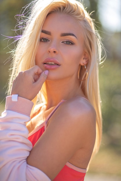 Closeup portrait of a fitness woman with long hair wears sport apprel posing in sunny day