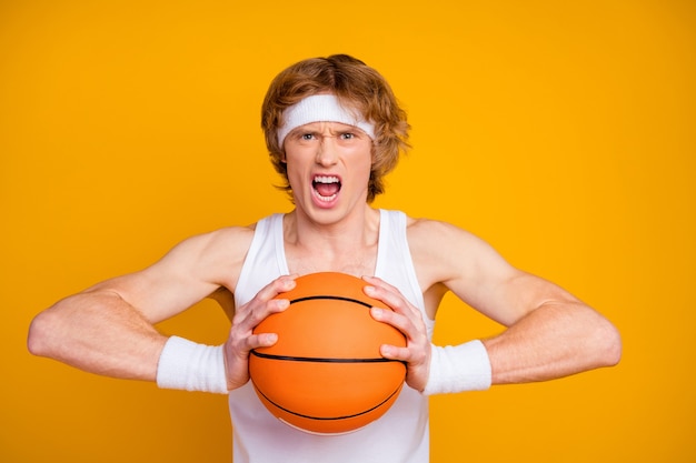 Closeup portrait of focused emotional guy sportsman holding in\
hand throwing ball