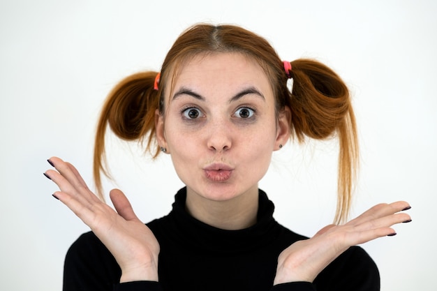 Closeup portrait of a funny redhead teenage girl with childish hairstyle isolated