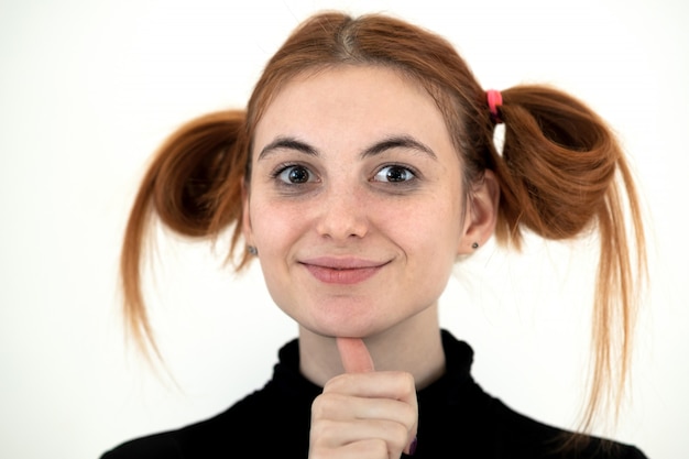 유치 한 헤어 스타일으로 행복 하 게 웃 고 흰색 backround에 웃 긴 빨간 머리 십 대 소녀의 근접 촬영 초상화.