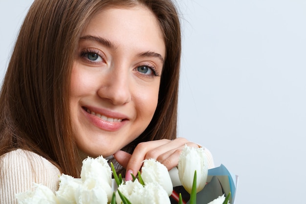 Foto ritratto del primo piano di una ragazza che tiene un mazzo di tulipani bianchi