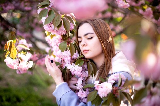 Closeup portrait of a girl near blooming Japanese cherry blossom sakura