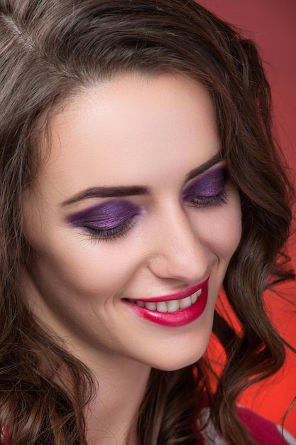 Closeup portrait girl with purple shadows for eyes and red lips on red background