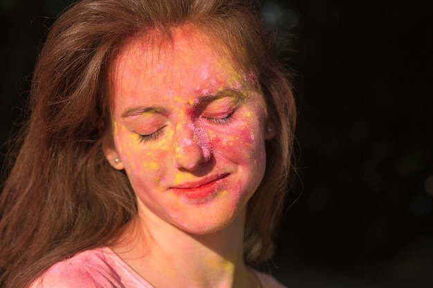 Photo closeup portrait of gorgeous brunette model covered with colorful holi paint