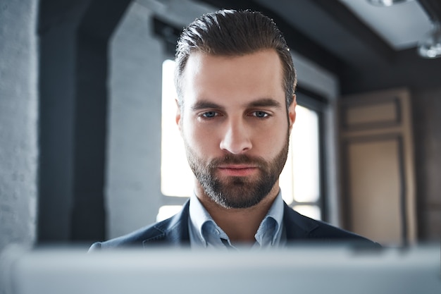 Closeup portrait of handsome bearded man in a suit looking a camera seriously