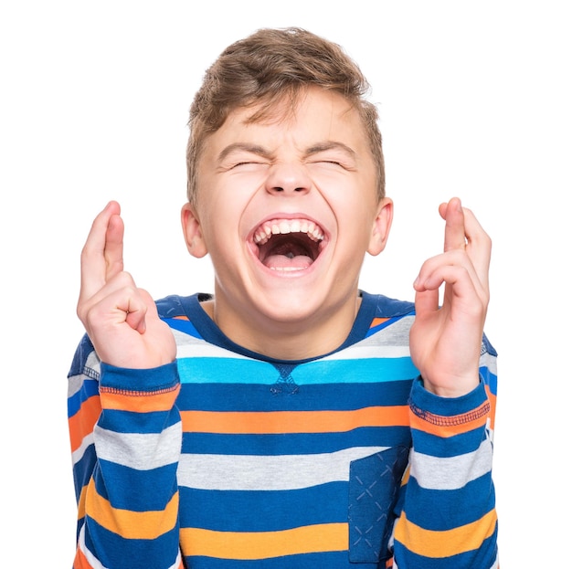 Closeup portrait of handsome hopeful teen boy crossing his fingers Beautiful human face expression and emotions Funny caucasian child making luck gesture with eyes closed isolated on white background