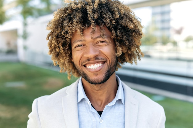 Photo closeup portrait of a happy charismatic confident curly haired brazilian or hispanic male successful entrepreneur business man standing outdoors looking at the camera smiling friendly