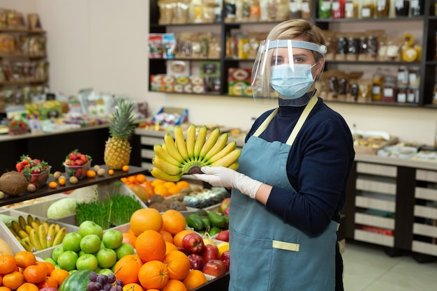 Closeup portrait of a happy smiling female grocery store worker wearing a protective mask