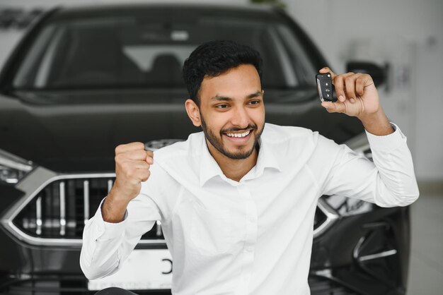 Photo closeup portrait happy smiling young man buyer showing keys of his new car