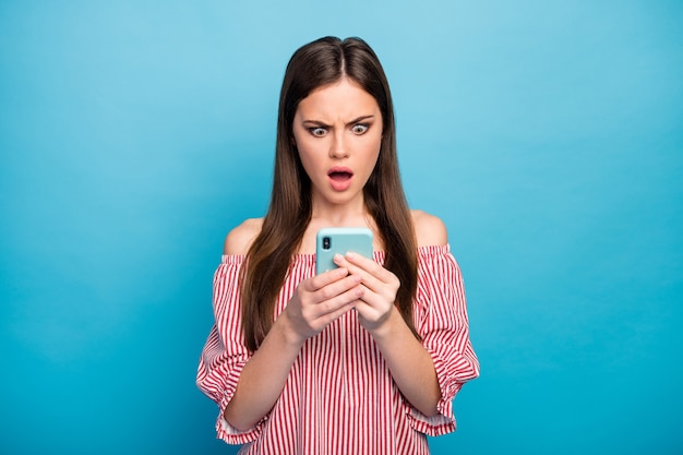 Closeup portrait of her she nice attractive lovely pretty stunned outraged longhaired girl using cell smm dislike reaction isolated over bright vivid shine vibrant blue color background