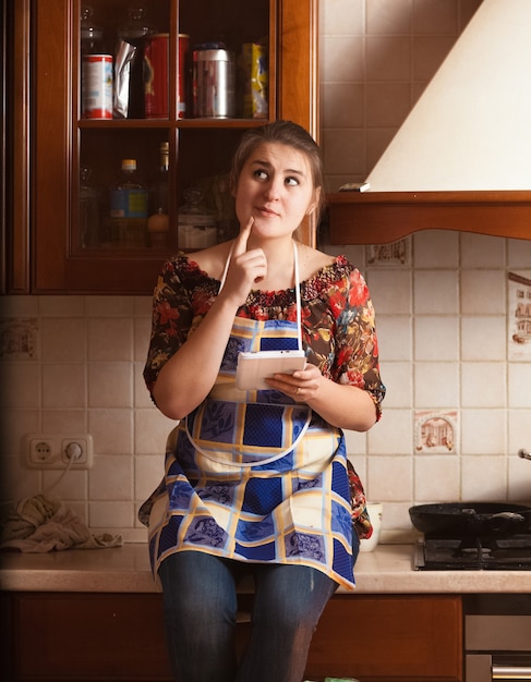 Ritratto del primo piano della casalinga che ricorda la ricetta del piatto