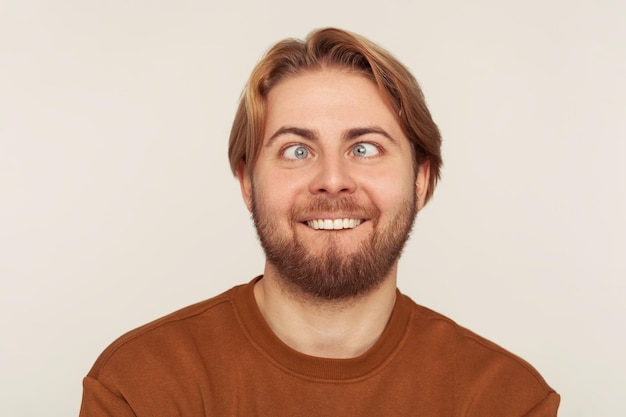 Closeup portrait of idiot dumb bearded man looking crosseyed with stupid smile fooling around making silly face