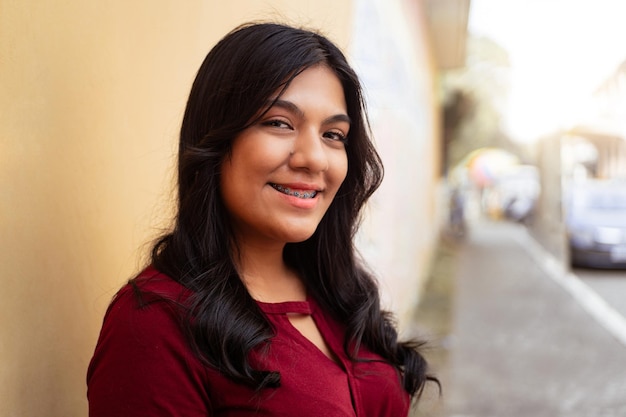 Closeup of portrait of latin american young woman smiling with brackets over street city