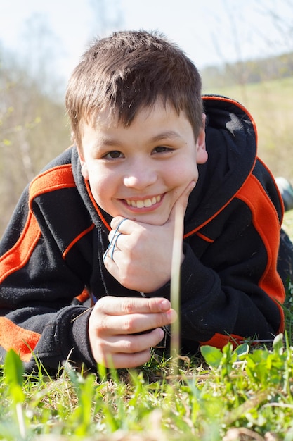 closeup portrait of laughing little boy lying on the grass
