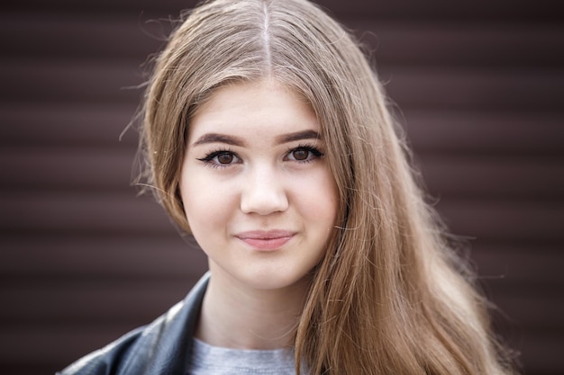 Closeup portrait of little beautiful stylish kid girl against a brown striped wall