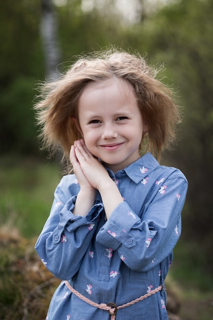 Closeup portrait of little girl of 5 years in the forest and looking at the camera