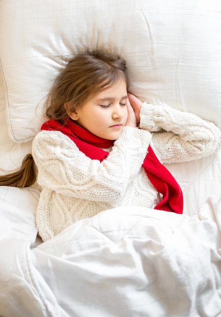 Closeup portrait of little girl in sweater sleeping at bed