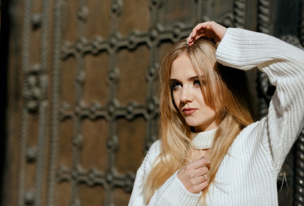 Closeup portrait of luxurious model with natural makeup posing near metal wrought door. Space for text