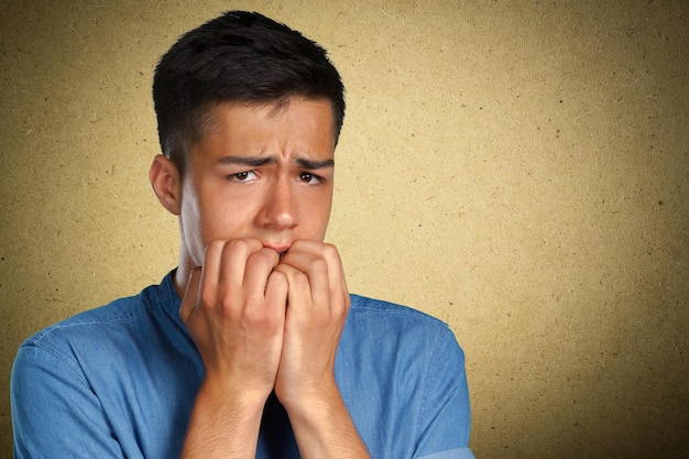 Closeup portrait of a man biting his nails and looking at camera