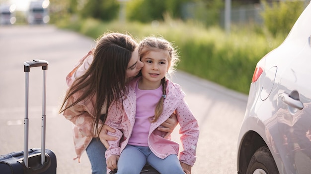 Closeup portrait of mom kiss her daughter in cheek during they waiting a trip little girl sitting on