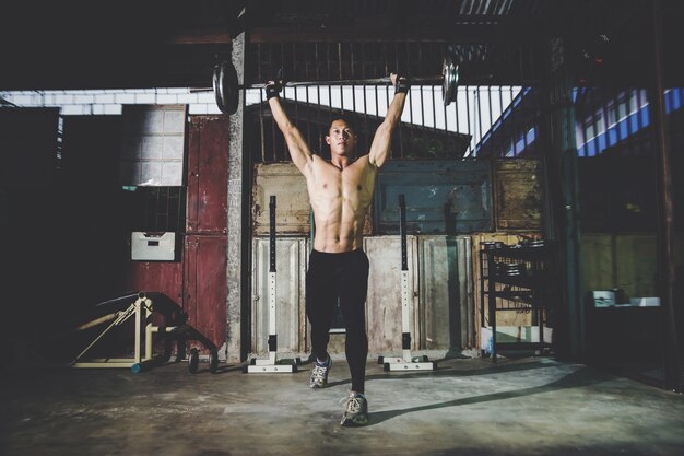 Closeup portrait of a muscular man workout with barbell at local gym 