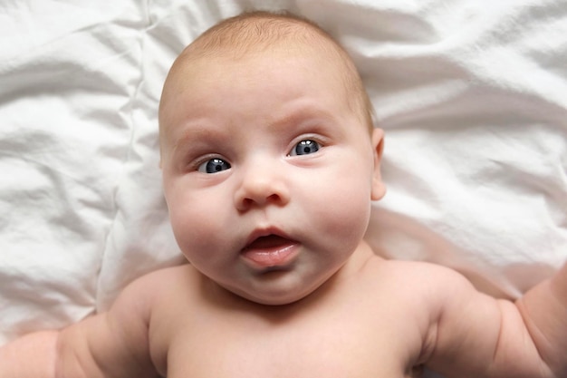 Closeup portrait of Newborn baby on white blanket Soft focus Infant is lying yawning One two week age Infant girl waking up on bed at home New life and growing up concept Real People