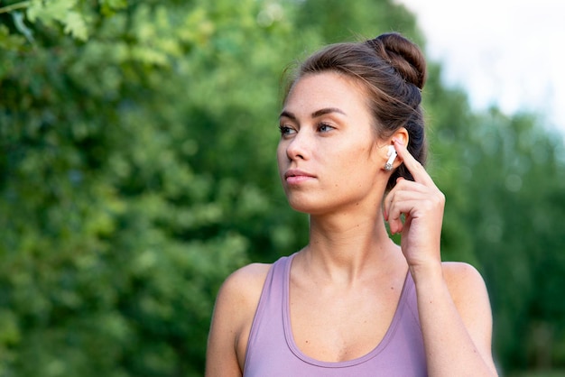 写真 歩きながら bluetooth ヘッドフォンを通して話している美しい若い物思いにふける女性のポートレート、クローズ アップ