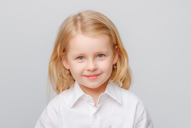 Крупным планом портрет милой маленькой девочки в белой рубашке на белом фоне