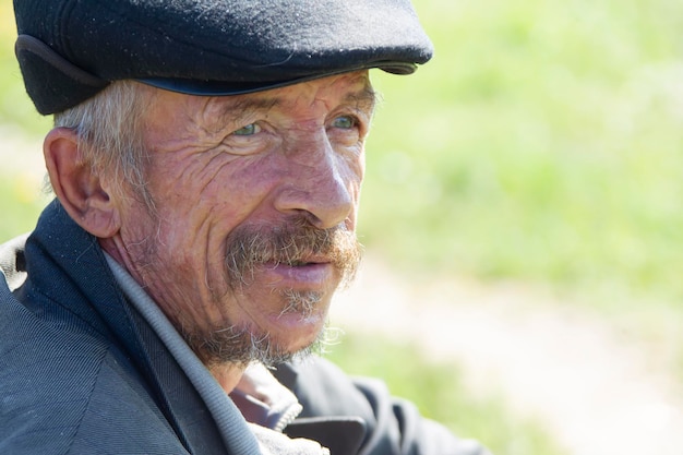 Closeup portrait of an old grandfather Russian elderly man in a cap