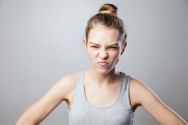 Closeup portrait, pangry, grumpy, skeptical young woman with bad attitude, arms crossed, looking at you isolated grey background. Negative human emotion, facial expressions, feelings