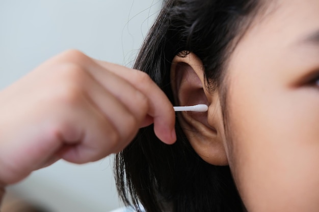 Closeup portrait of person hand putting cotton bud stick inside her ear