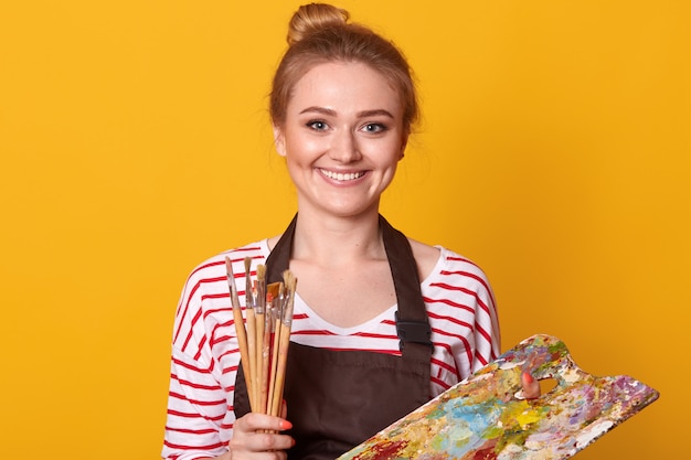 Closeup portrait of positive adorable cute painter wearing stripped sweatshirt