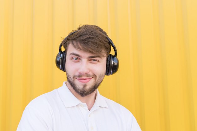 Closeup portrait of a positive young man with headphones on the head while listening to music.