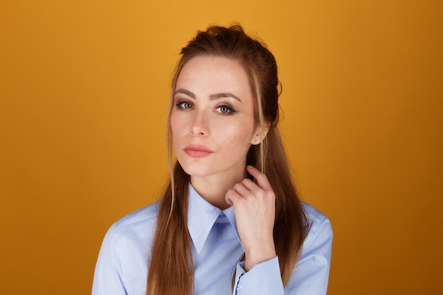 Closeup portrait of pretty yong woman with bright makeup in a studio isolated over the yellow background.