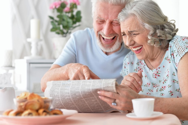Closeup portrait of a senior couple with newspaper at home