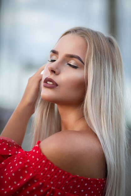 Closeup portrait of sensual blonde model with long blonde hair, posing with closed eyes