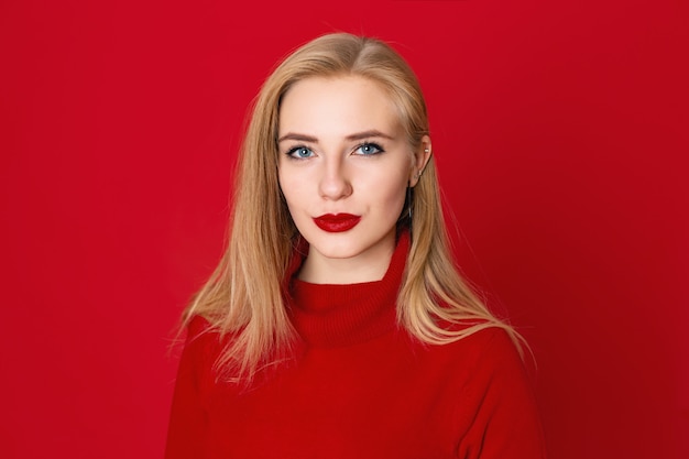 Closeup portrait of sensual blonde woman against a red background in the studio.