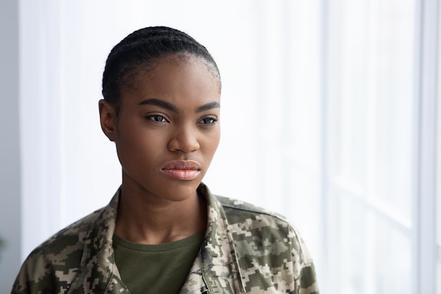 Photo closeup portrait of serious black female soldier standing near window indoors